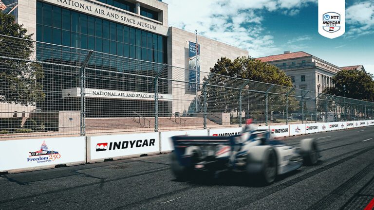 Carro da IndyCar em alta velocidade passando em frente ao National Air and Space Museum no circuito de rua de Washington, DC.